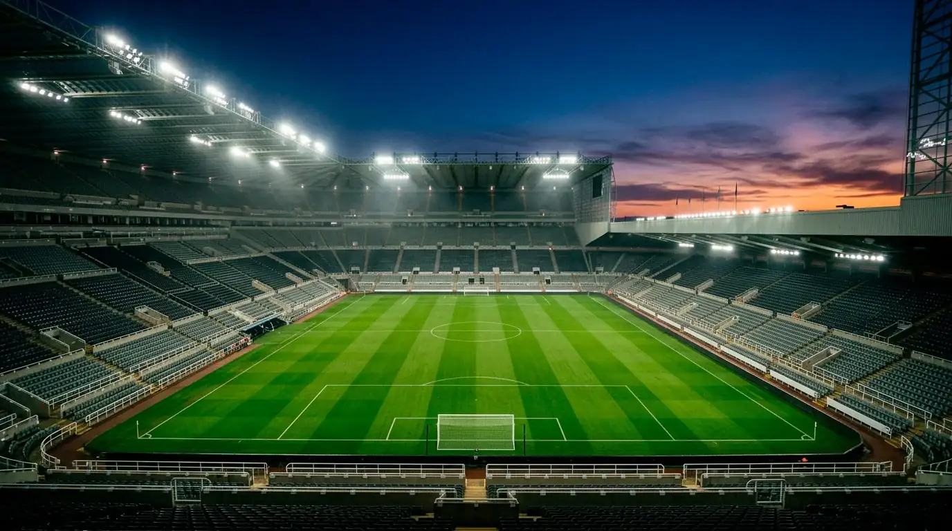 Stadion-Tribüne in Abendstimmung mit grünem Rasen und beleuchteten Fluchtlichtmasten